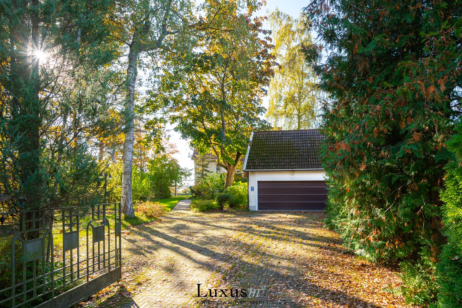 Kaunis rautaportti ohjaa pihalle. Kahden auton tallissa on hybrideille latauspisteet.